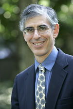 image of Mike Leeds wearing glasses, in a blue dress shirt and suit