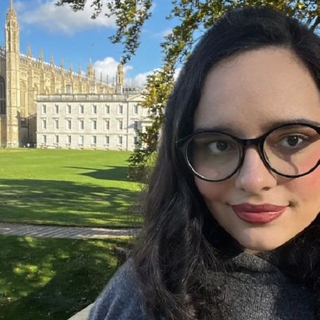 image of Andrea Morales in a grey sweater in from of Cambridge University