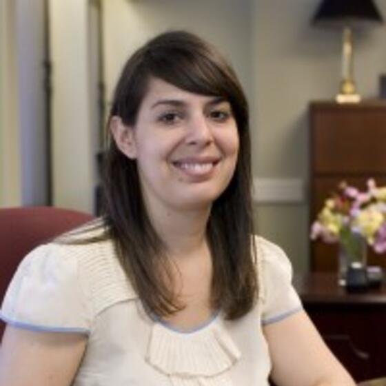 Lauren Ellman in a white shirts sitting in a chair smiling and staring into the camera