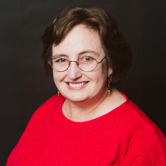 Robin Kolodny in a red shirt smiling and staring into the camera