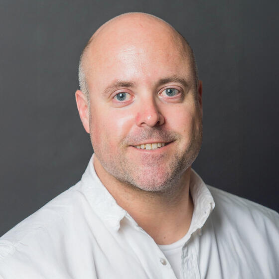 Michael Ingram in a white shirt smiling and staring into the camera