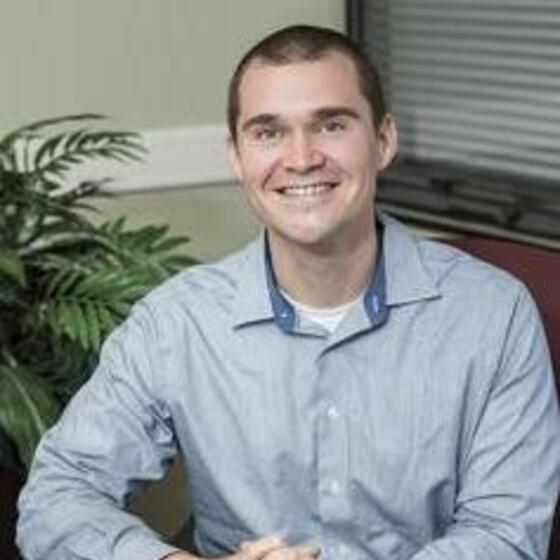 David V. Smith sitting in an office with a blue shirt smiling and staring into the camera