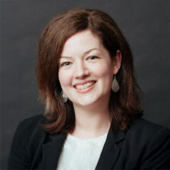 Emma Irvin in a black suit coat smiling into the camera