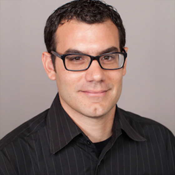 James M. Delise in a black shirt smiling and staring into the camera