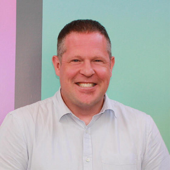 Kevin Haugh wearing a light blue shirt smiling and staring into the camera