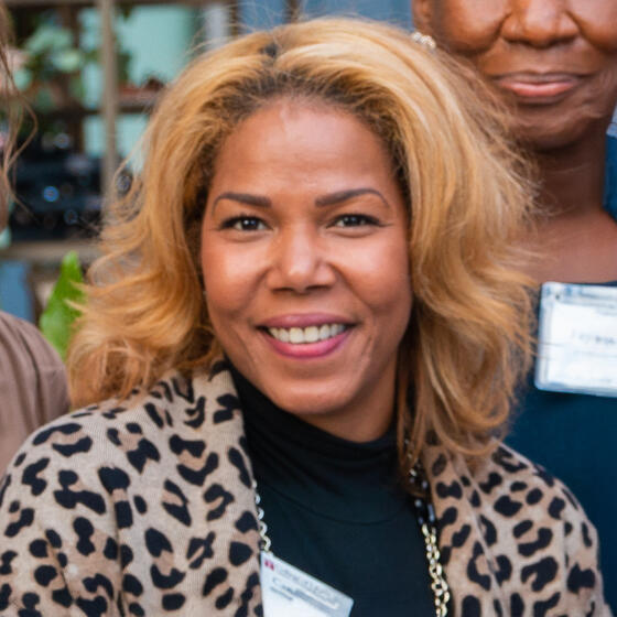 Camille V. Elliott wearing a leopard pattern jacket and black shirt smiling and staring into the camera