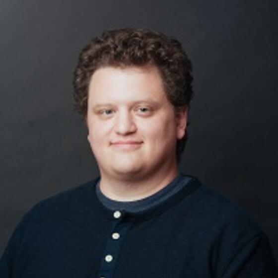 Nicolaos Catsis in a black shirt smiling and staring into the camera