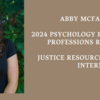 image of Abby smiling at the camera wearing a black blouse standing in front of green trees