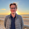 image of Hippolyte standing at the beach wearing glasses and smiling at the camera