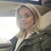 Catherine Schroeder sitting a car with a green coat on staring into the camera