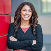 Joanne Metzger wearing a black shirt with her arms crossed smiling and staring into the camera