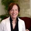 Kathryn Hirsh-Pasek in white suit coat with a black shirt smiling and staring into the camera
