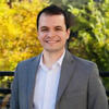 Lucas de Souza Martins standing outside in a gray suit coat smiling into the camera