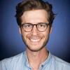 image of Austin wearing glasses and a blue shirt smiling at the camera