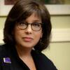image of Pam wearing glasses wearing a suit looking at the camera