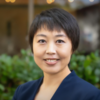 image of Lin wearing a navy blue suit standing outside smiling at the camera