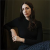 Liz Moore sitting in a chair wearing a black turtleneck with her hands crossed
