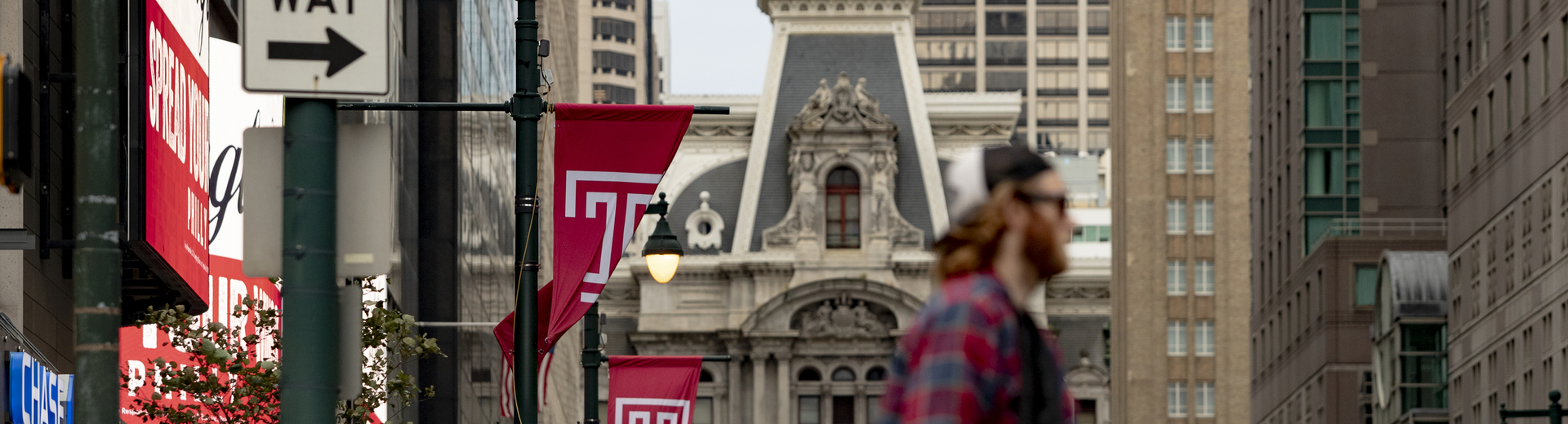 photo of city hall with temple flags and student in foreground