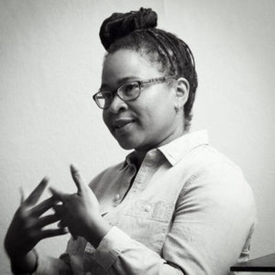 black and white image of Renee Gladman sitting and talking with her hands in motion