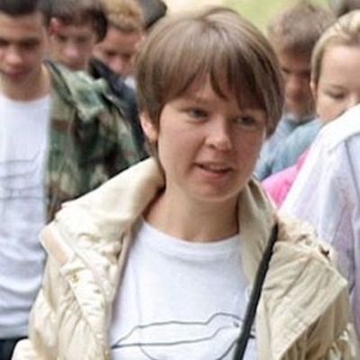 image of Yevgeniya Chirikova standing in a crowd wearing a white tee shirt and cream jacket