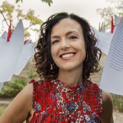 image of Rosa standing smiling wearing a red blouse with flowers