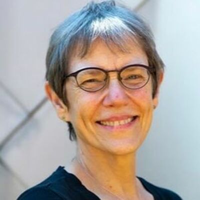 image of Sally wearing glasses, smiling looking at the camera wearing a black top