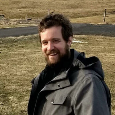 image of Will standing in a field wearing a wind jacket smiling at the camera
