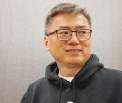 image of Curtis wearing a Detroit swweatshirt and glasses smiling and looking away from the camera