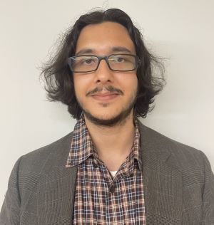 image of Ignacio wearing glasses in a plaid shirt and brown blazer