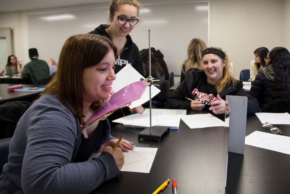 image of Neuro students smiling and sitting at a table doin an experiment