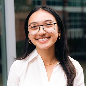 image of Angela wearing glasses and a white blouse smiling at the camera