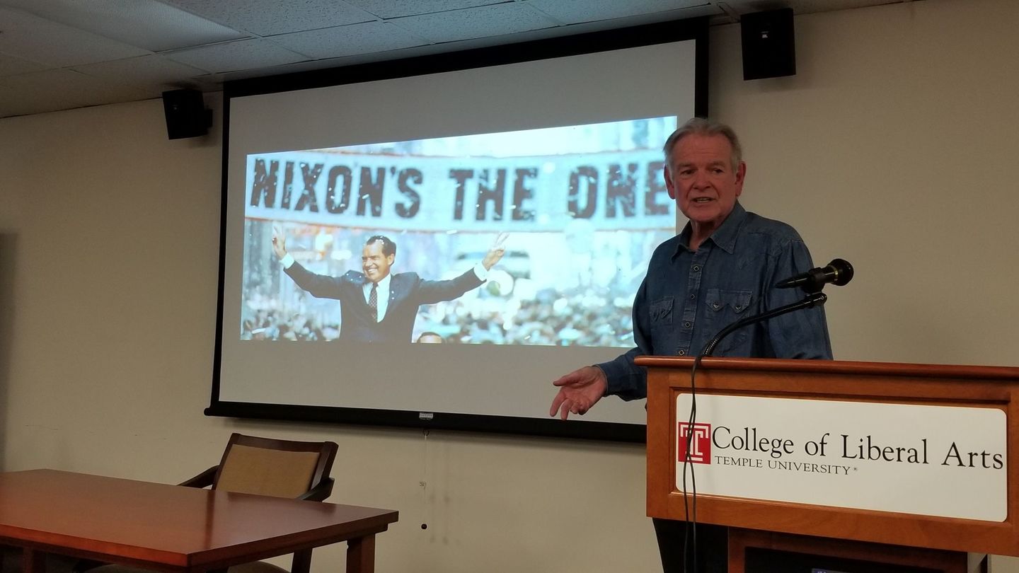 Professor Ralph Young speaks at podium in front of a screen that reads "Nixon's the one"