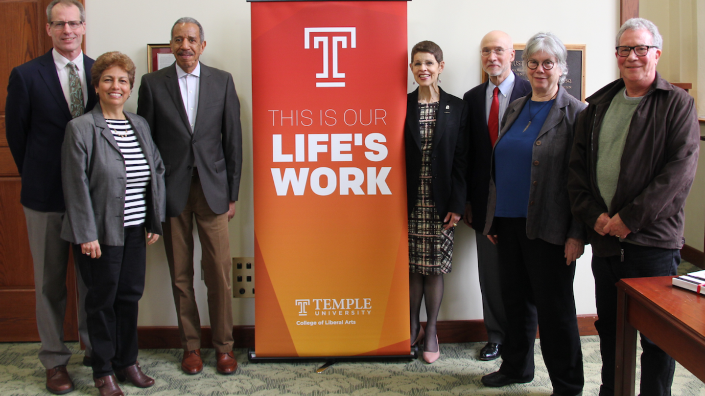 Retiring faculty members stand around a banner that reads "This is our life's work"