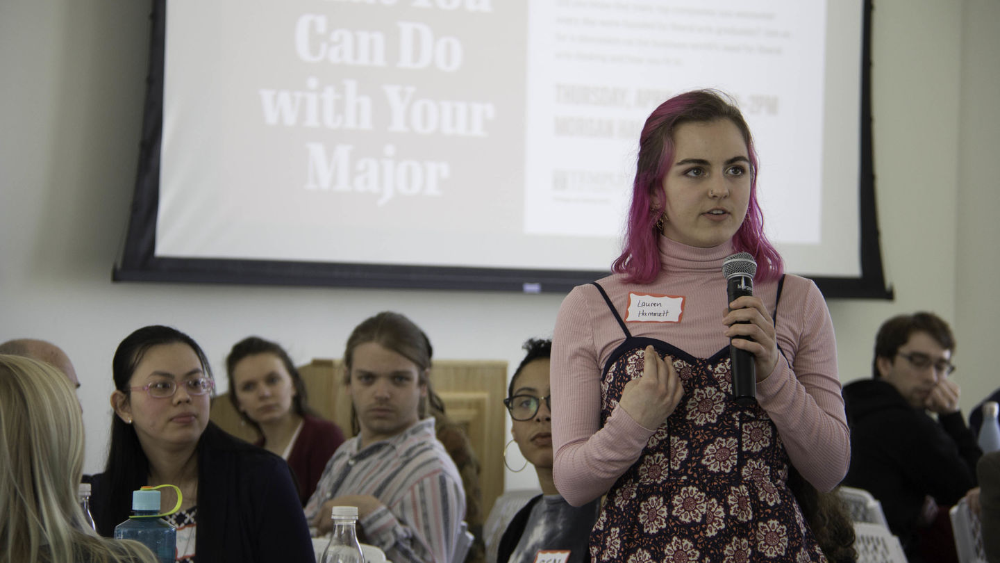 A student speaks at the Leonard and Helena Mazur Networking Event in front of a screen that reads "What can you do with your major?"
