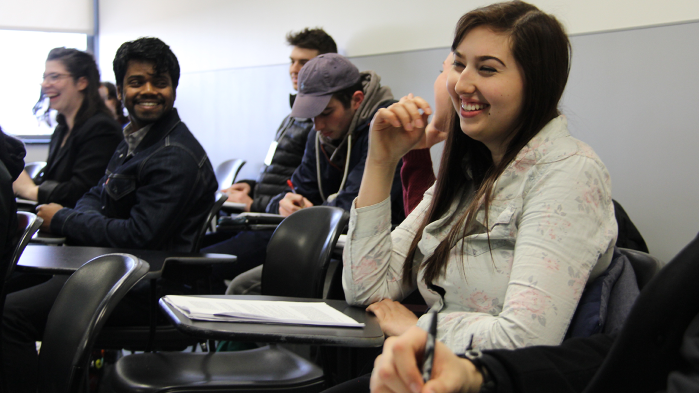 Students sit at their desks while laughing and engaged in class