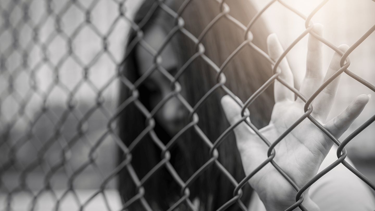 Black and white image of a young girl behind a fence