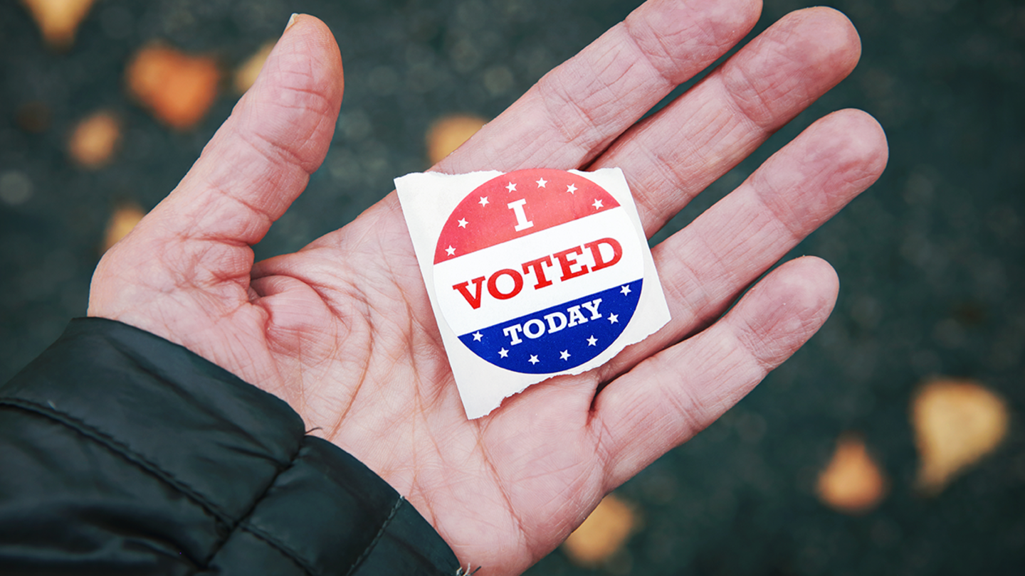 A hand holds an "I voted" sticker