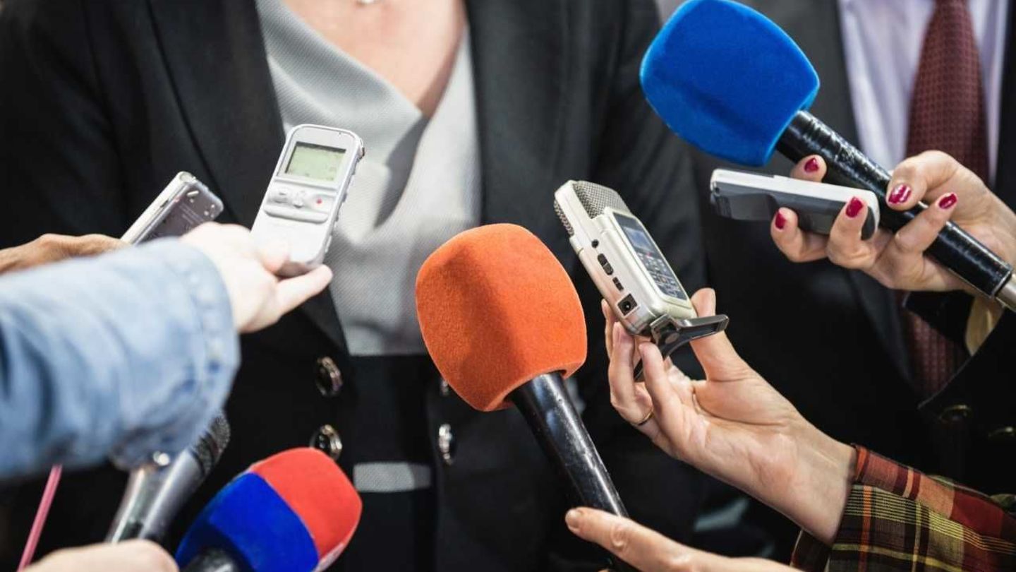 Reporters hold microphones and recording devices