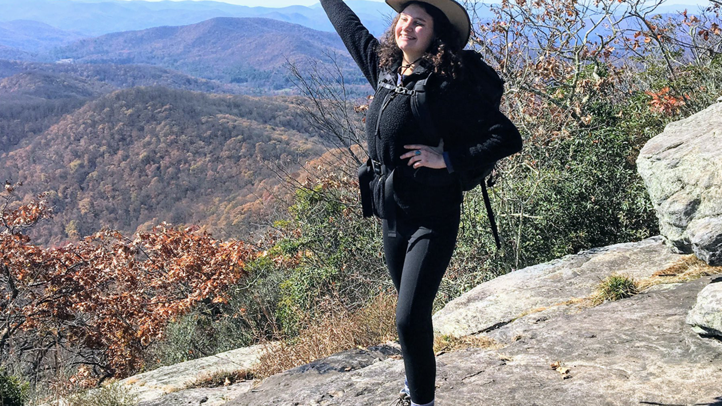 College of Liberal Arts alumna Jillian Eller stands atop a hill
