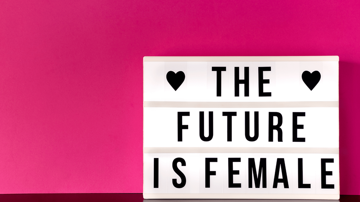 A letterboard reads "The Future is Female" against a pink background