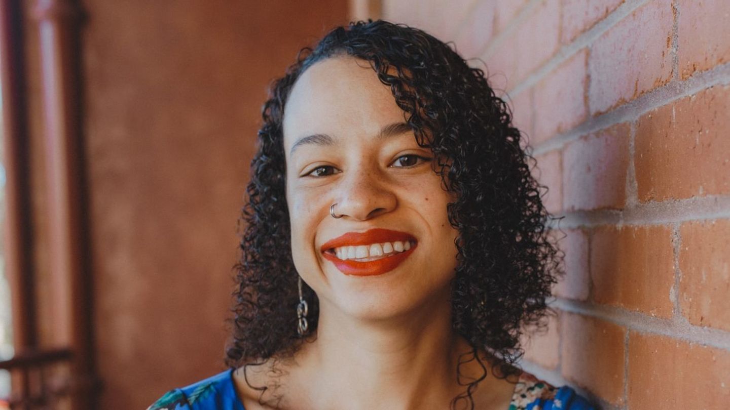 Carissa Harris believes fantasy shows like The Lord of the Rings: The Rings of Power and House of the Dragon are appealing because of audiences’ desire to imagine a world and time different from their own. Image of Carissa Harris standing in a floral-printed outfit.