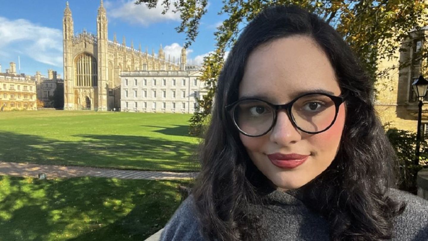 image of Andrea Morales in a grey sweater in from of Cambridge University