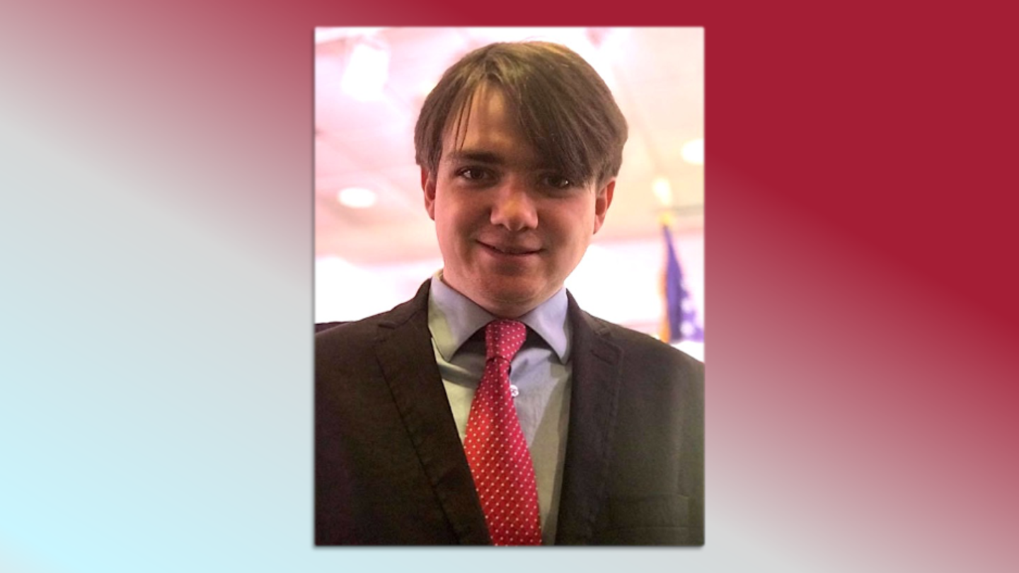 image of Luke Christopher in a red tie, blue button down shirt and black suit jacket