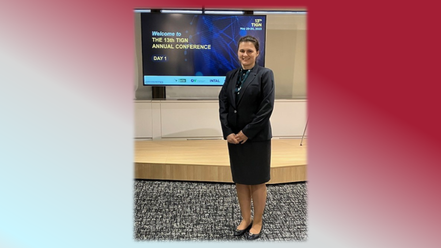 image of Olga standing in a blue skirt suit in from of a conference screen