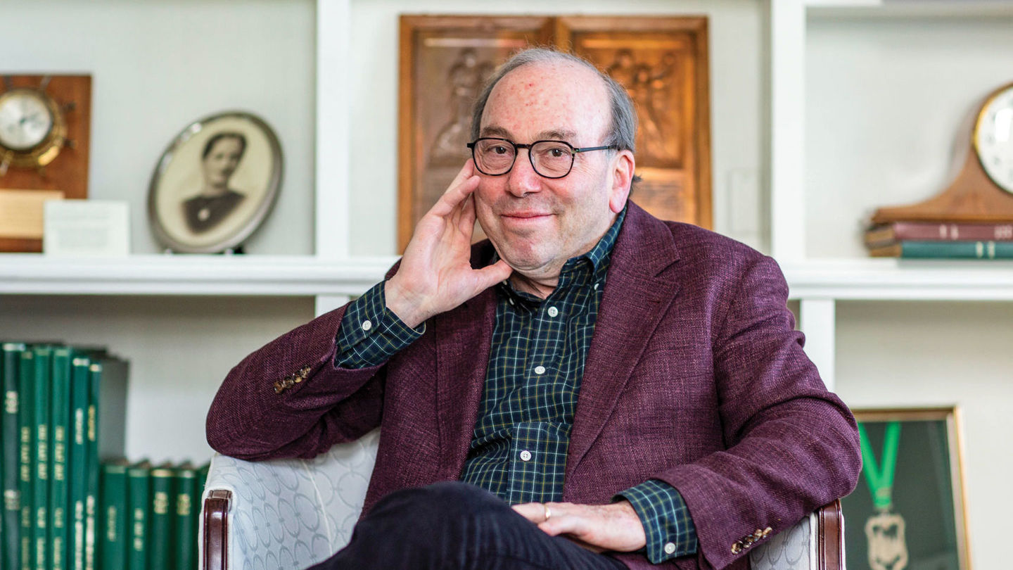 image of Witney sitting with his hand on his chin wearing a maroon blazer and blue dress shirt