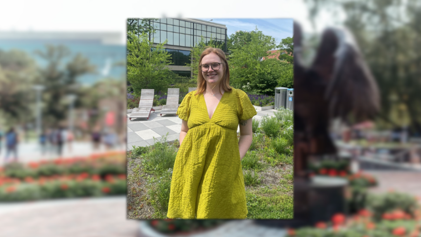 image of Clare standing wearing glasses and a pea green dress