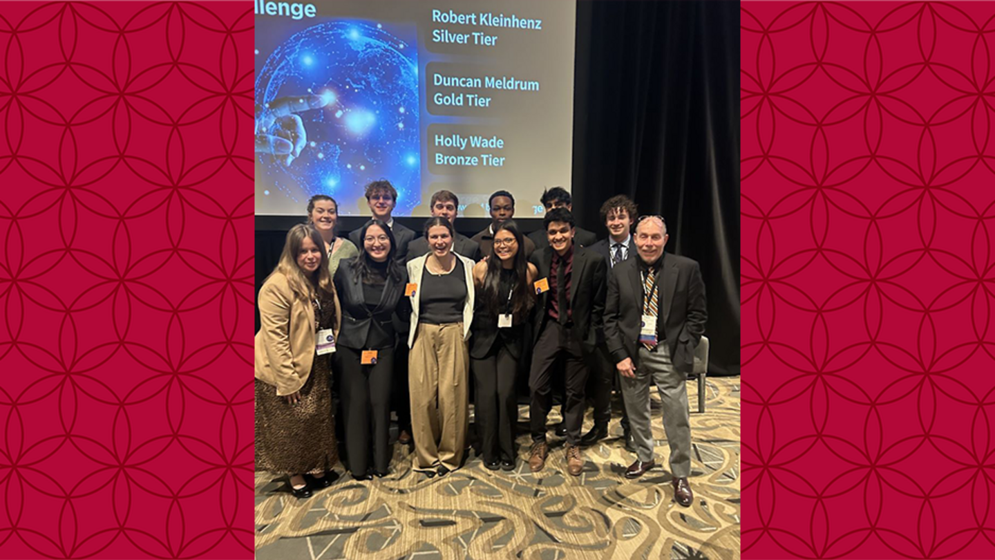 Temple Economics Society and Professor Chris Swann image of students and Chris Swann standing in front of a projection screen in a group photo